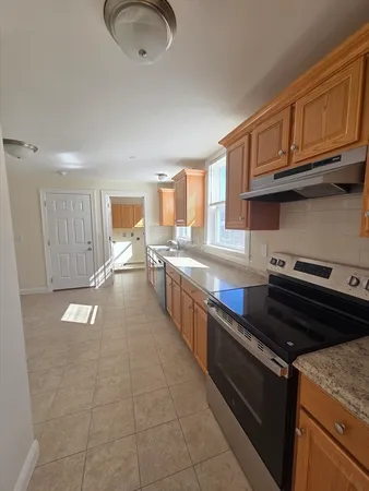 a large kitchen with stainless steel appliances granite countertop a stove a sink dishwasher and cabinets with wooden floor