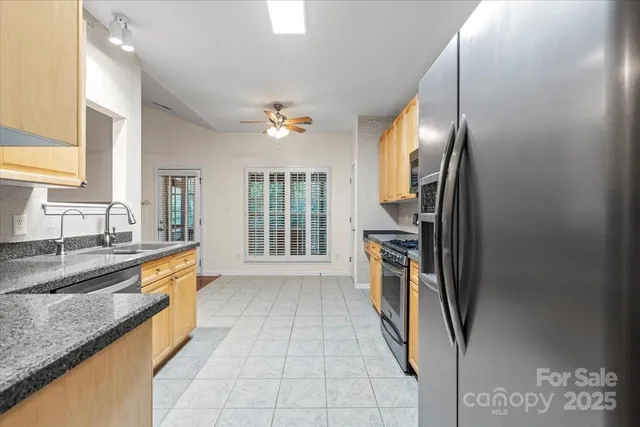 a large kitchen with stainless steel appliances granite countertop a stove a sink and a refrigerator