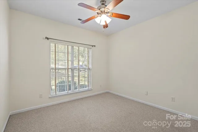 a view of an empty room with chandelier fan