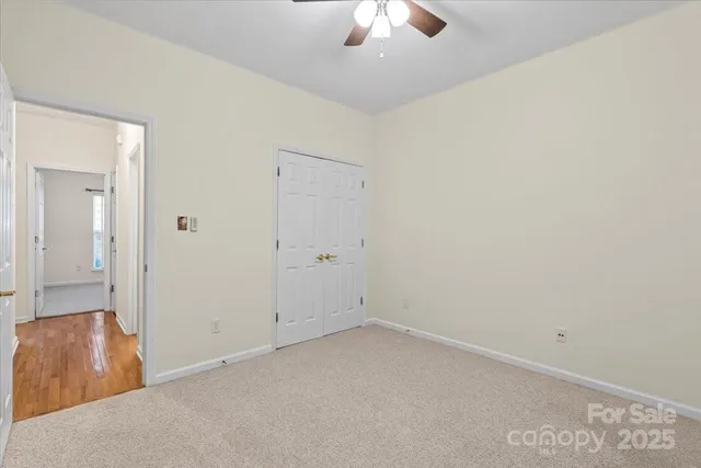 an empty room with windows and chandelier fan