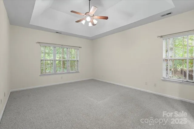an empty room with windows and ceiling fan