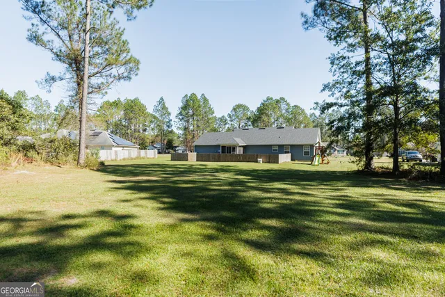 a view of a big house with a big yard and large trees