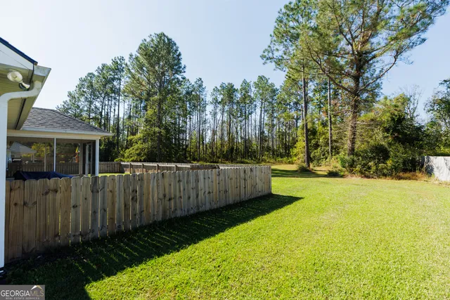a view of a backyard with wooden fence and large trees