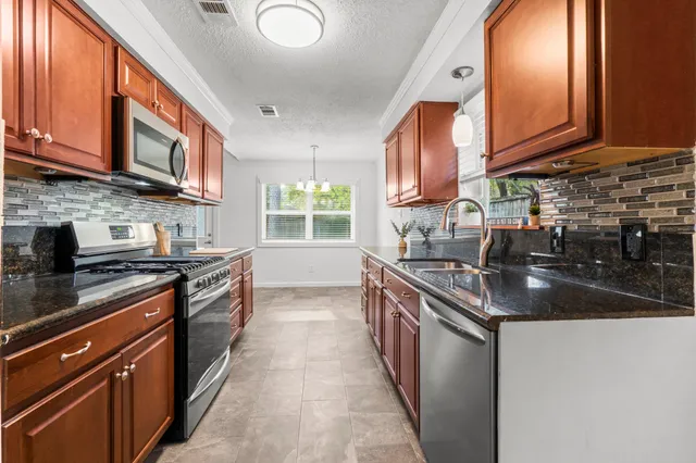 a kitchen with stainless steel appliances granite countertop a stove a sink and a microwave