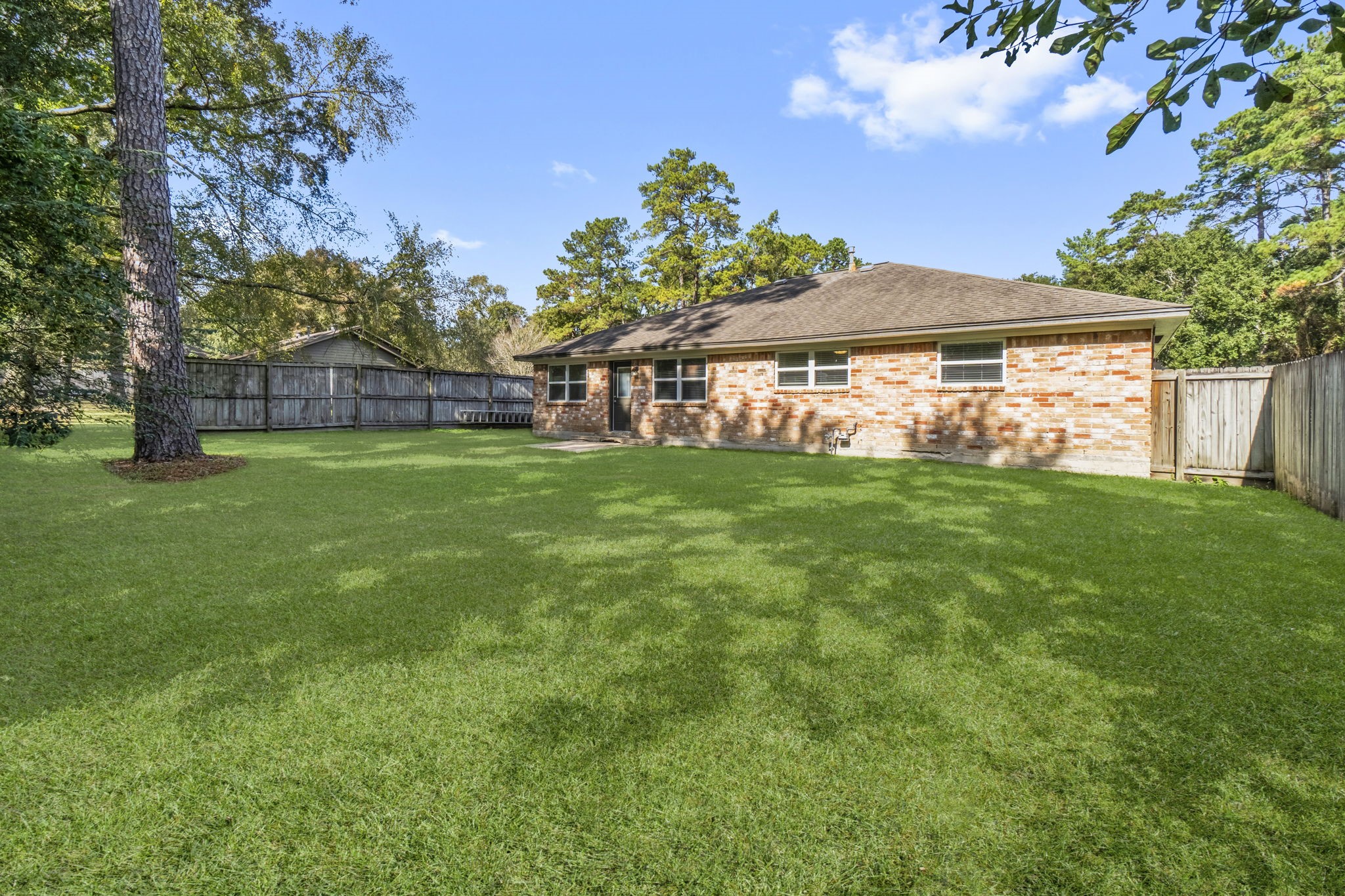 3223 Kentwood Drive Spring, TX 77380 - Photo 29 of 31 Deep backyard view showcasing the impressive size of the lot. The open grassy area and established tree offer endless possibilities for entertaining or future enhancements such as a garden, playset, or fire pit.
