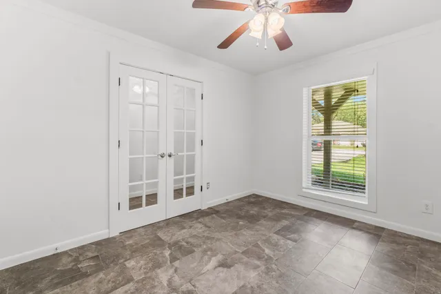 an empty room with windows and fan