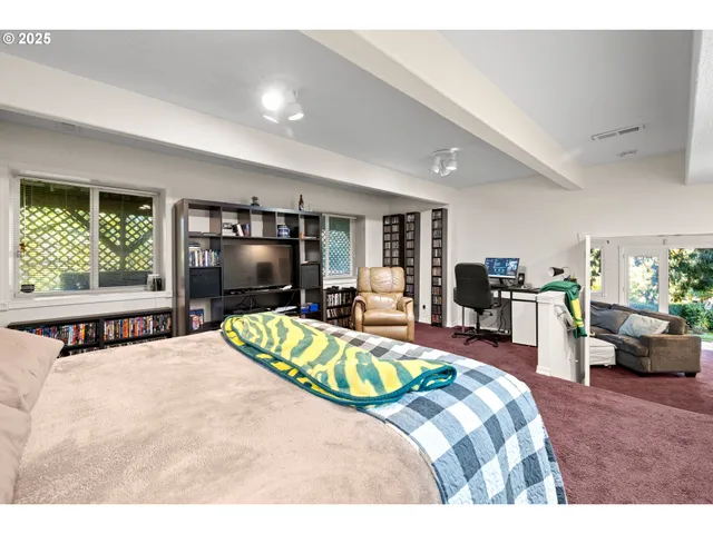 a bedroom with a bed and large windows