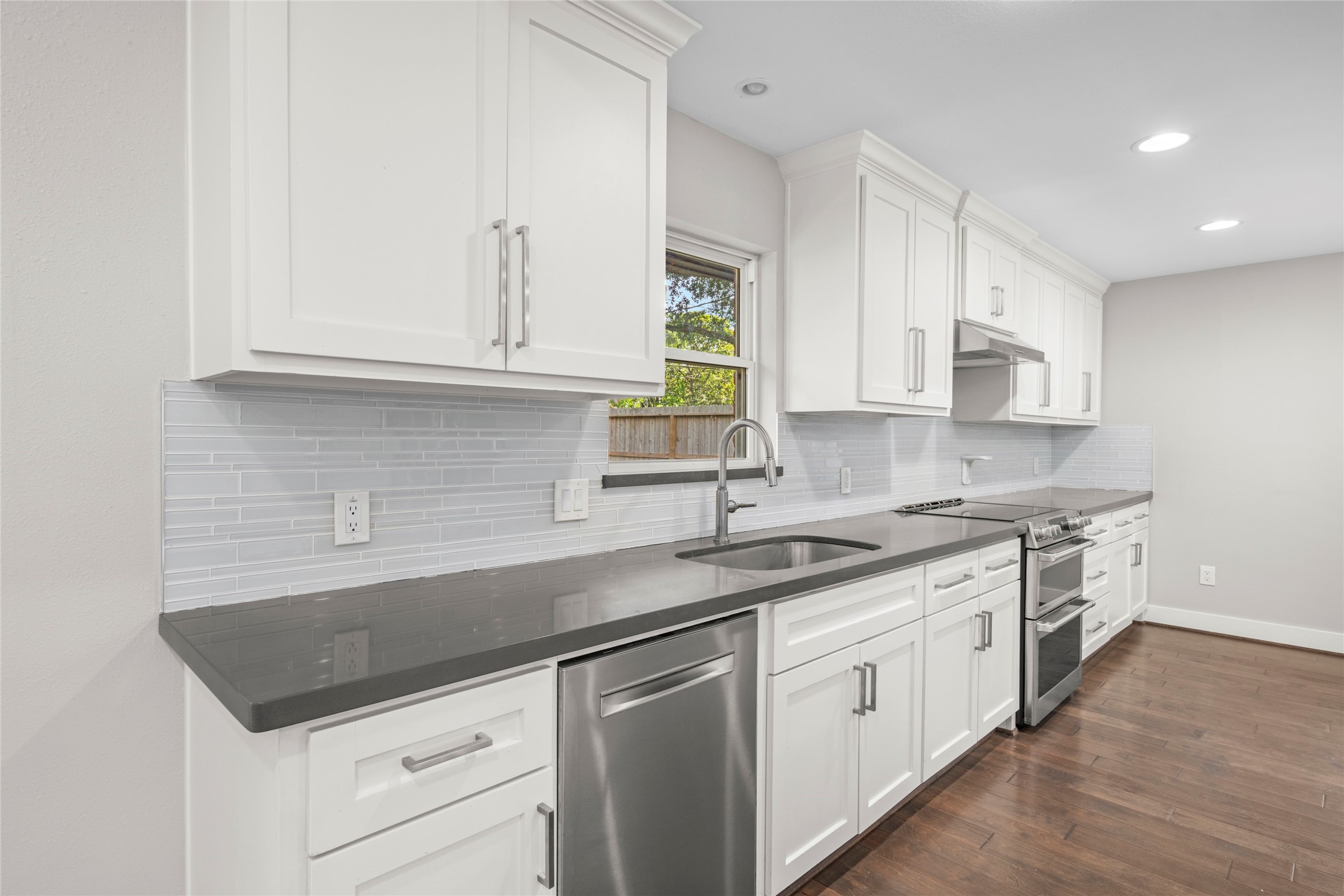 5723 Spellman Road Houston, TX 77096 - Photo 10 of 29 The kitchen includes a farmhouse-style sink, quartz countertops, tile backsplash, soft-closing cabinetry and drawers, and a window overlooking the backyard.