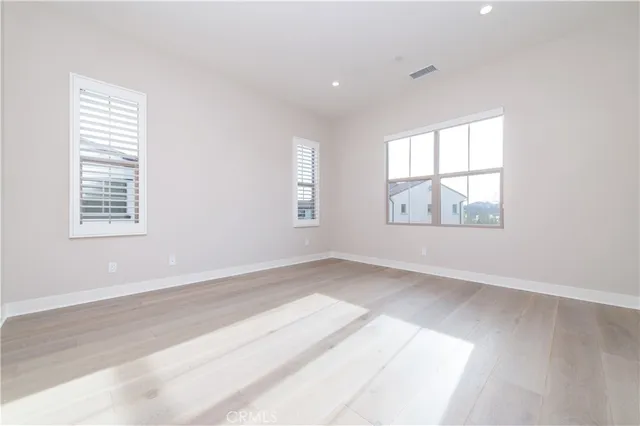an empty room with wooden floor and windows