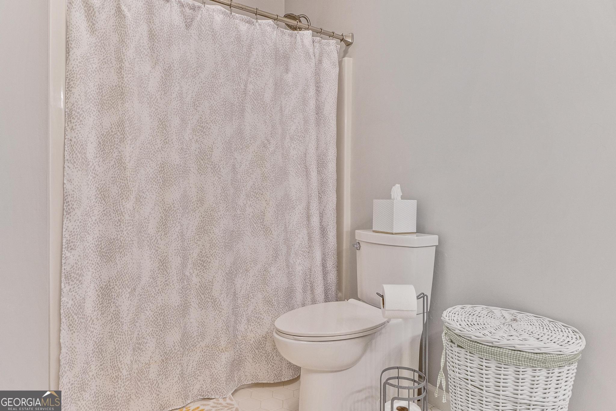 204 Carriage Way Macon, GA 31210 - Photo 21 of 28 a white toilet sitting next to a shower curtain