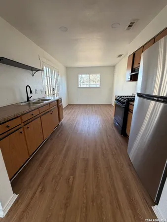 a kitchen with sink a refrigerator and wooden floor