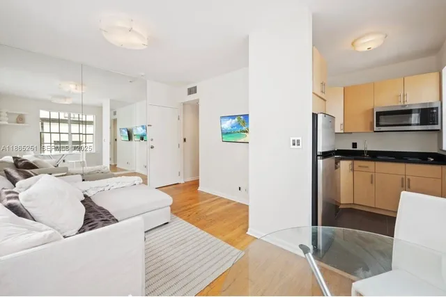 a living room with stainless steel appliances furniture a rug and a kitchen view