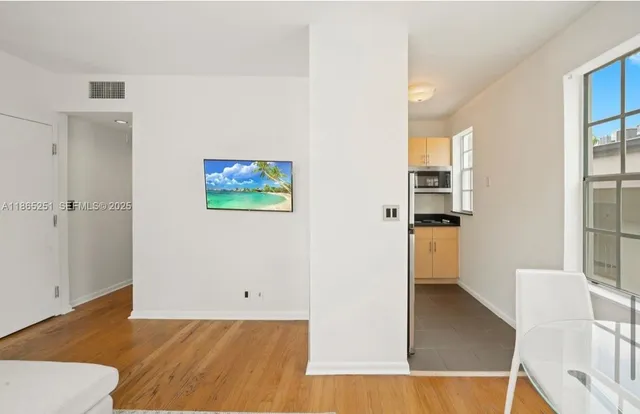 a view of a kitchen with wooden floor and a living room