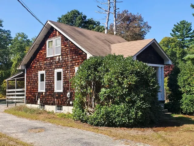a view of a house with wooden fence next to a yard