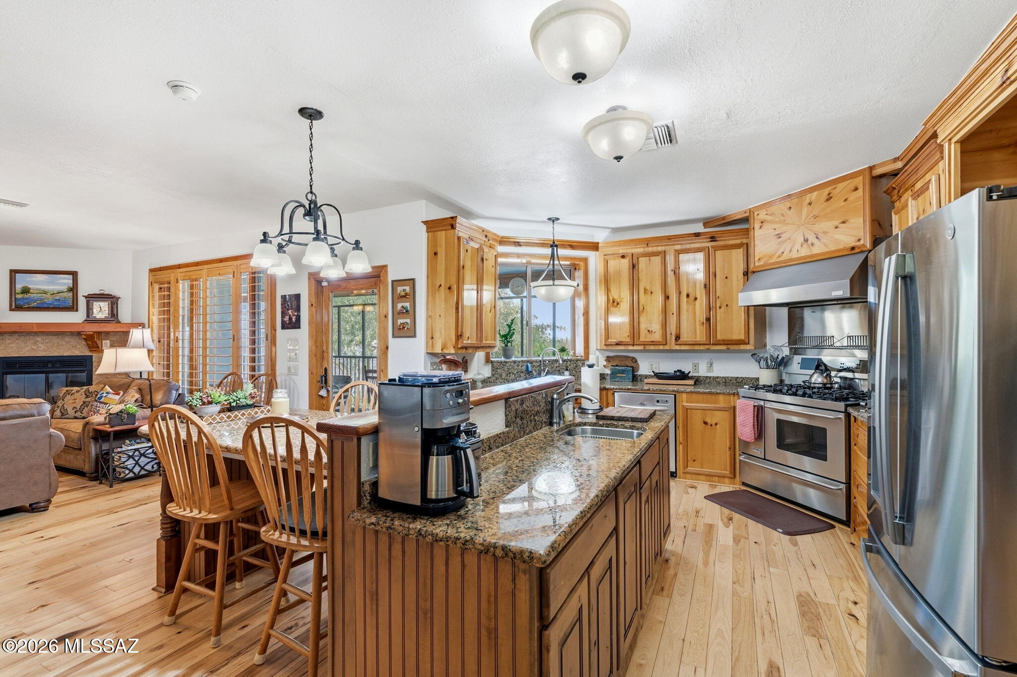 12810 West Gunsmoke Road Tucson, AZ 85736 - Photo 15 of 51 a kitchen with stainless steel appliances granite countertop a stove top oven a sink dishwasher a dining table and chairs with wooden floor