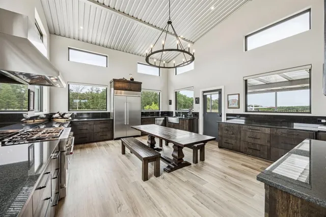 a kitchen with stainless steel appliances granite countertop a stove top oven a sink dishwasher a dining table and chairs with wooden floor