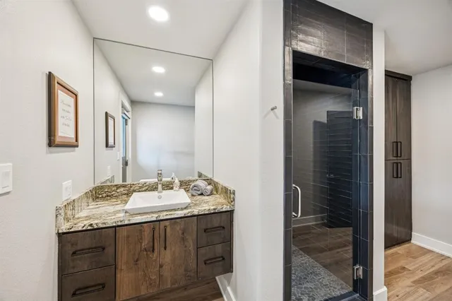 a bathroom with a granite countertop sink a mirror and shower