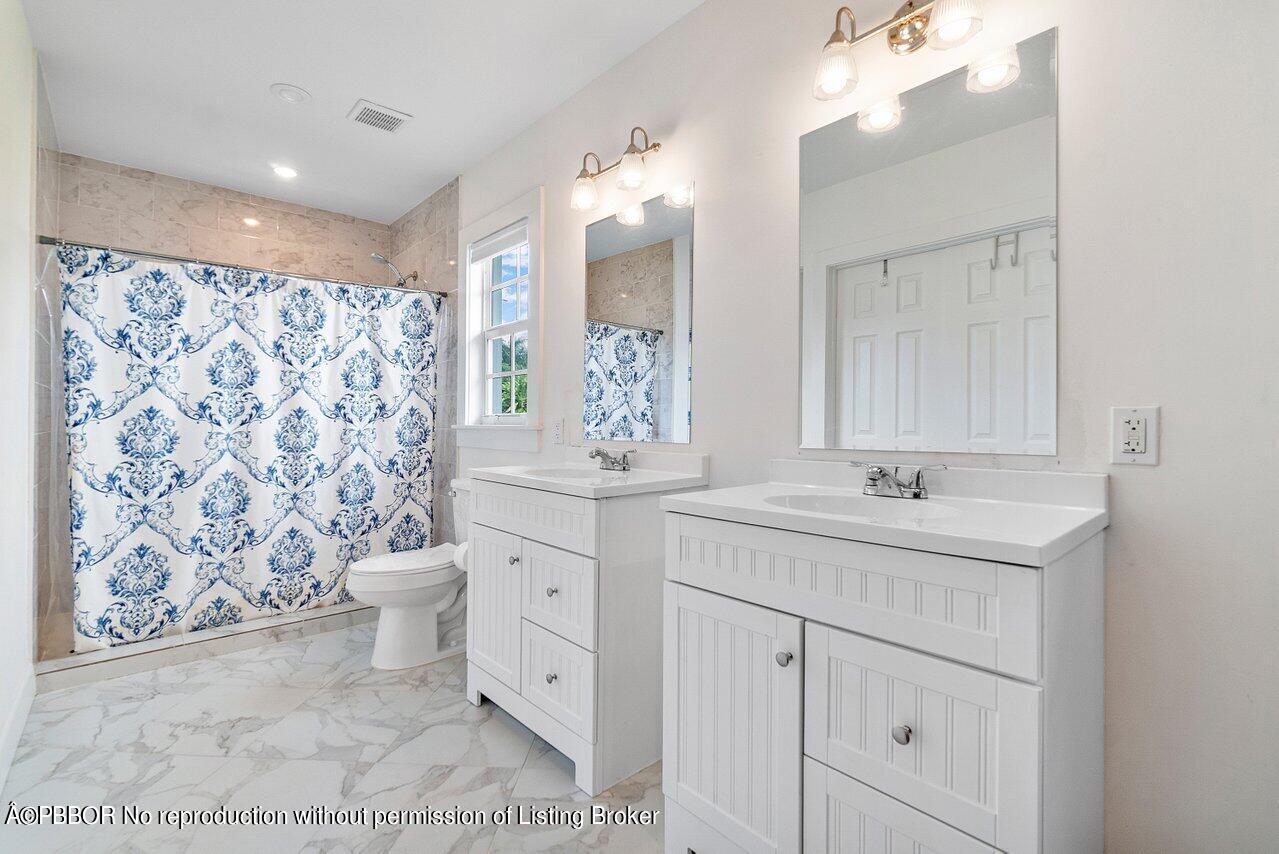 231 Argyle Road West Palm Beach, FL 33405 - Photo 16 of 17 a bathroom with a sink toilet a mirror a vanity and shower