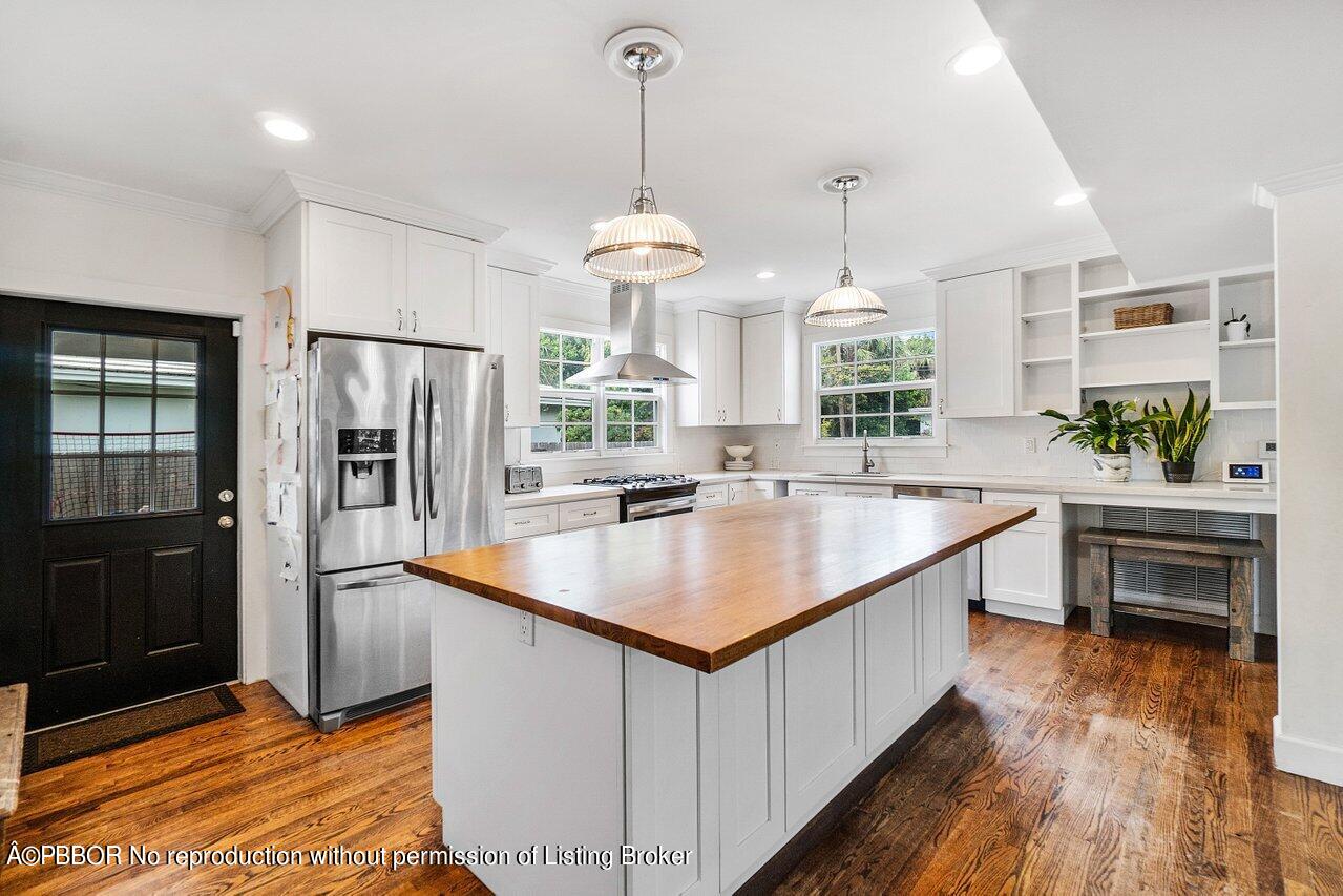 231 Argyle Road West Palm Beach, FL 33405 - Photo 5 of 17 a kitchen with stainless steel appliances granite countertop a refrigerator a sink dishwasher a stove and a dining table with wooden floor