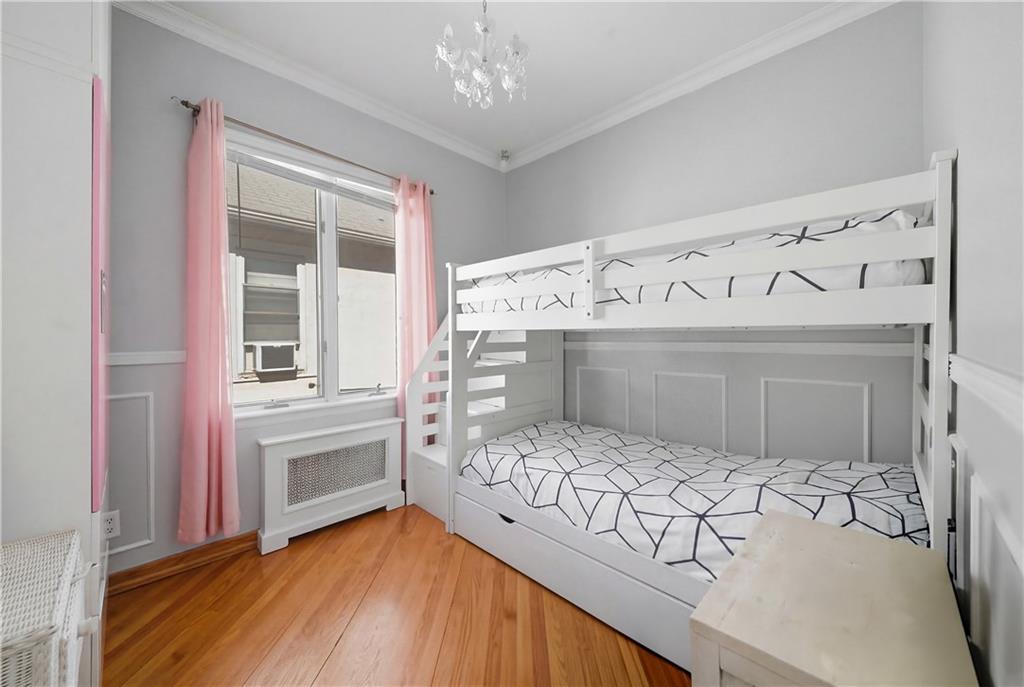 1730 East 4th Street Brooklyn, NY 11223 - Photo 19 of 24 a bedroom with a large bed and a chandelier