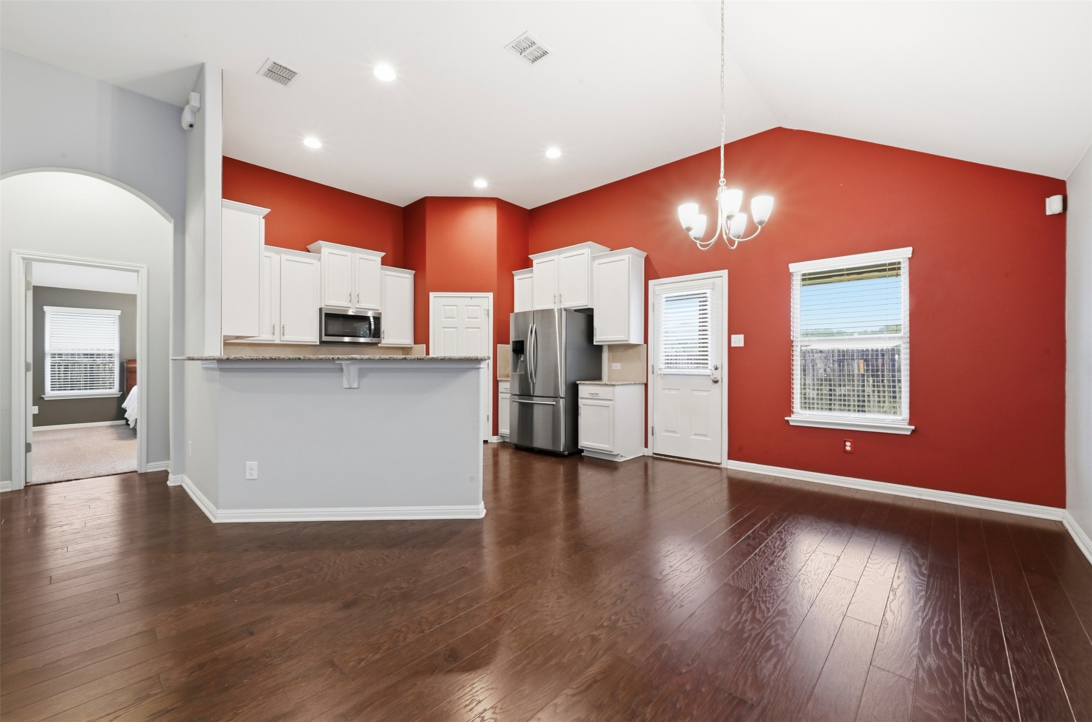 13116 Alans Way Manchaca, TX 78652 - Photo 8 of 25 Open-concept kitchen and dining area featuring vaulted ceilings, wood-finish flooring, white cabinetry, and stainless steel appliances