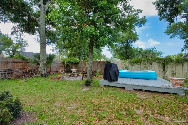 a view of a backyard with wooden fence and a bench