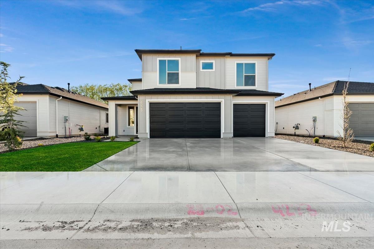 Modern two-story residence featuring a light gray and white exterior with black trim and black garage doors