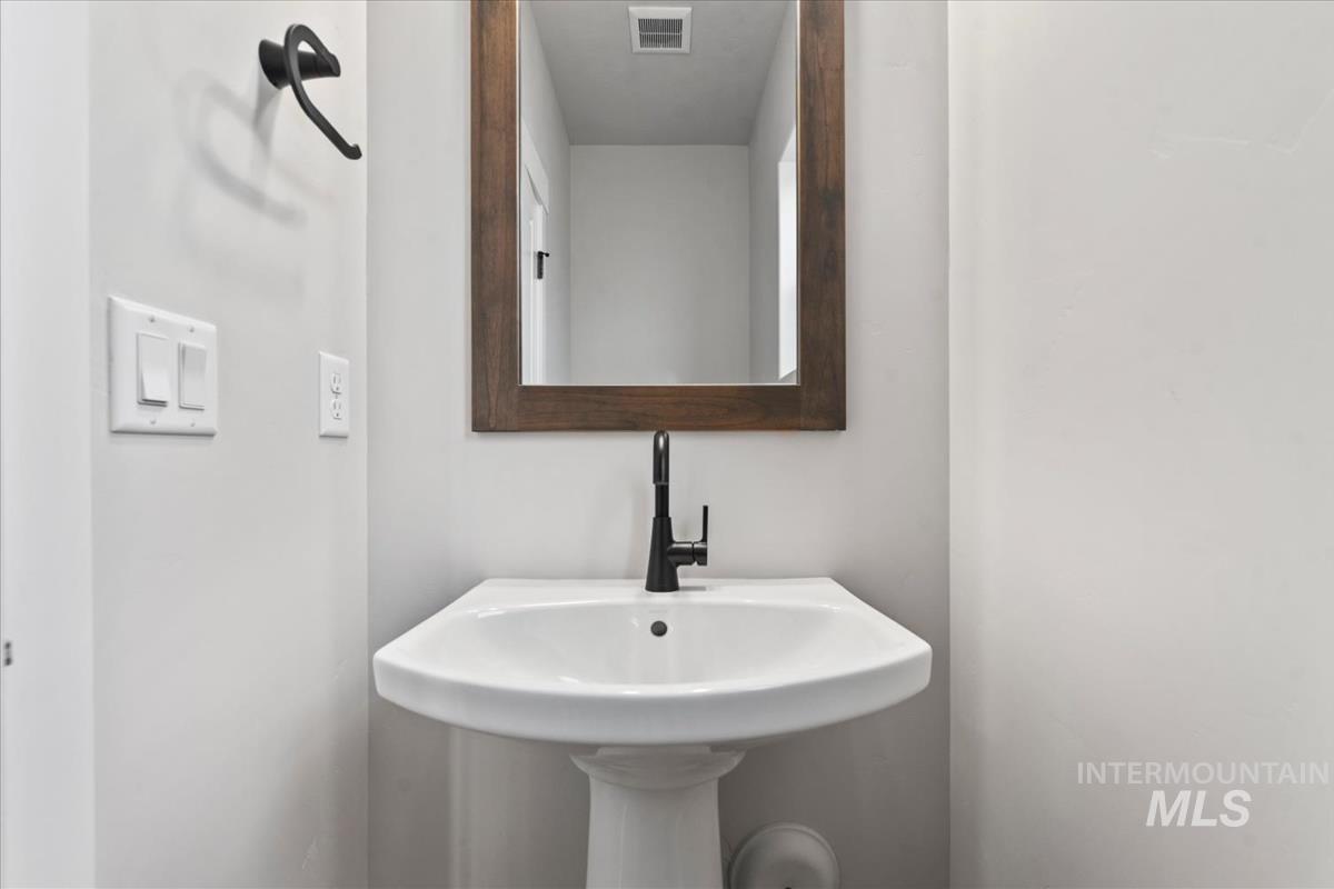 4223 Tropic Way Caldwell, ID 83607 - Photo 18 of 42 Pedestal sink with matte black faucet, framed mirror, and light gray wall paint