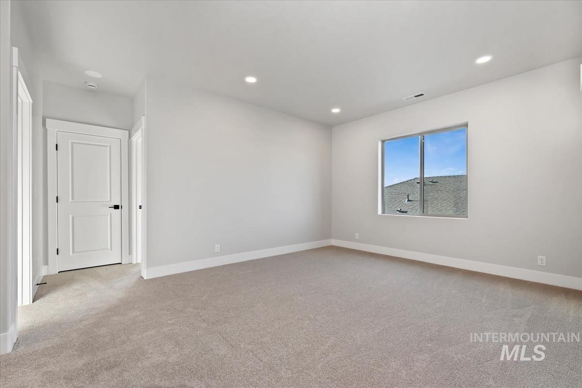 4223 Tropic Way Caldwell, ID 83607 - Photo 26 of 42 Spacious room featuring neutral carpeting, light gray walls, recessed lighting, and a window with a sloped roofline visible outside