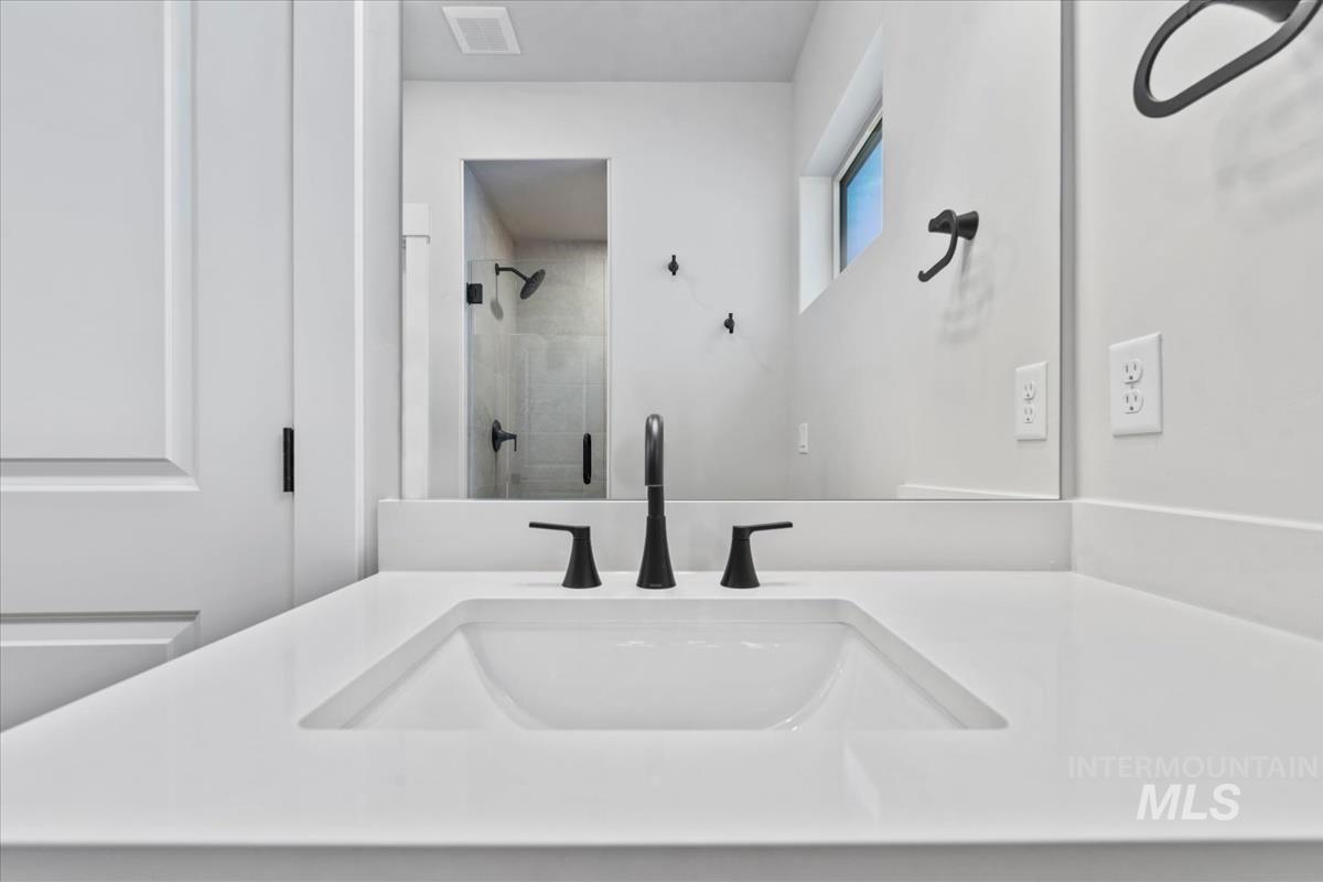 4223 Tropic Way Caldwell, ID 83607 - Photo 33 of 42 White vanity with an integrated rectangular sink, matte black faucet, and full-width mirror