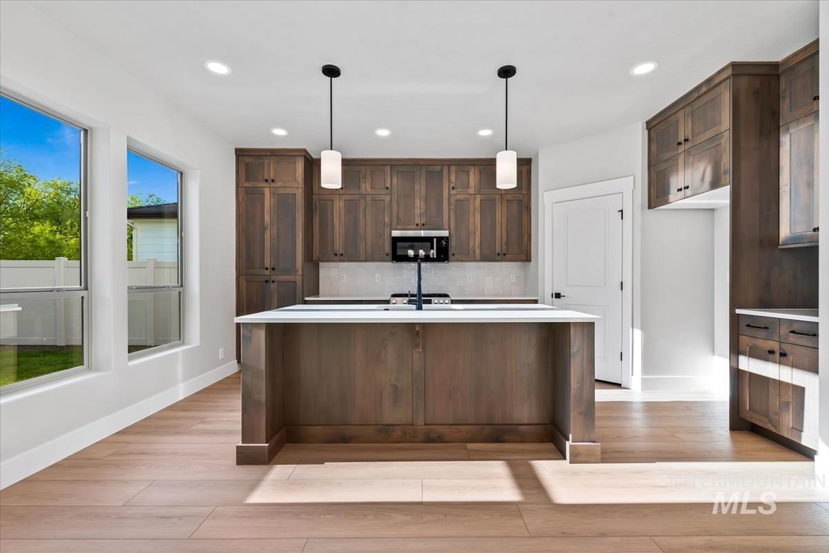 4223 Tropic Way Caldwell, ID 83607 - Photo 5 of 42 Kitchen featuring a large central island with white countertop, wood-finish flooring, recessed lighting, and expansive windows