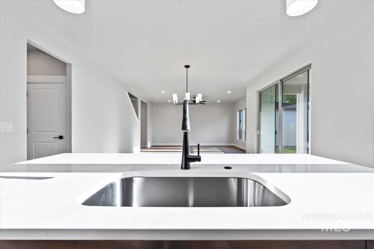 4223 Tropic Way Caldwell, ID 83607 - Photo 9 of 42 Kitchen island featuring a stainless steel undermount sink, black matte faucet, and white countertop