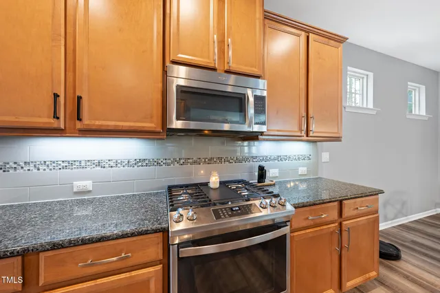 a kitchen with stainless steel appliances granite countertop a sink stove and microwave