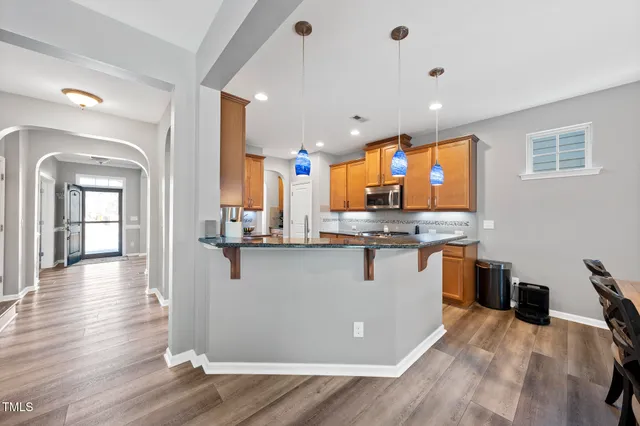 a kitchen with stainless steel appliances granite countertop a refrigerator a sink dishwasher a stove and white countertops with wooden floor