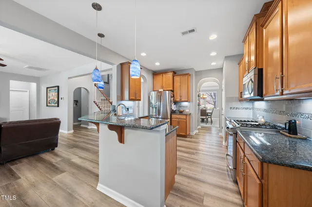 a kitchen with stainless steel appliances granite countertop a sink a stove and a wooden floors