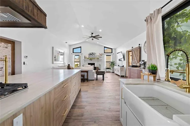 a large living room with stainless steel appliances granite countertop couches a fireplace with wooden floor