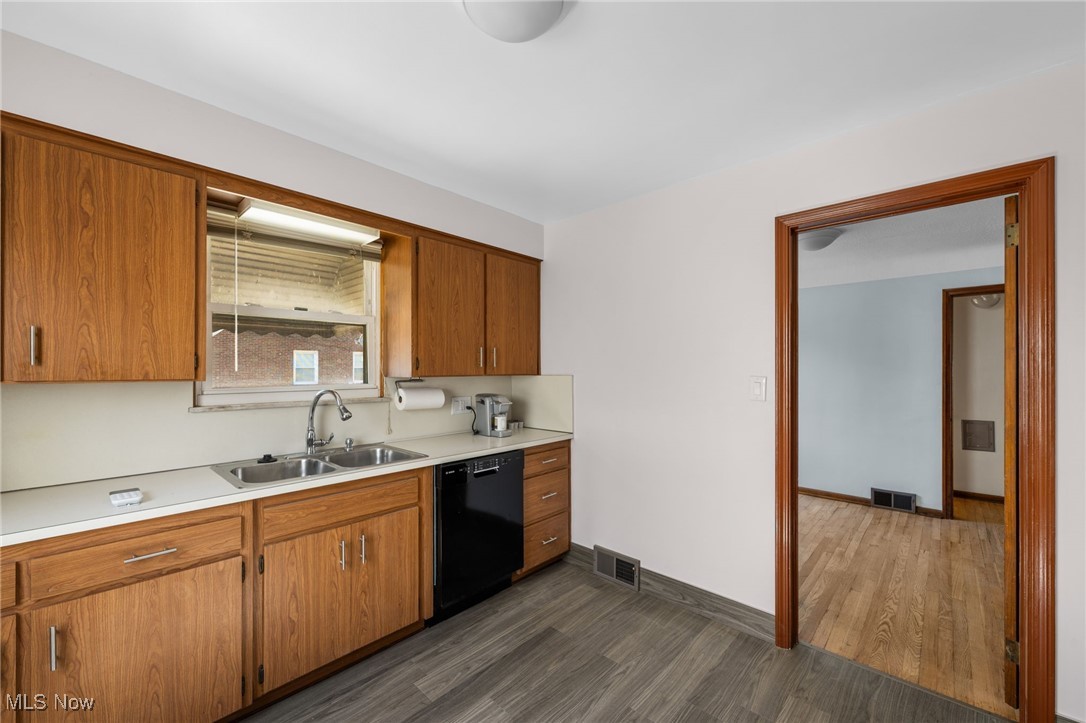 18122 Nottingham Road Cleveland, OH 44119 - Photo 10 of 29 Kitchen featuring brown cabinetry, light countertops, dark wood-style floors, and black dishwasher