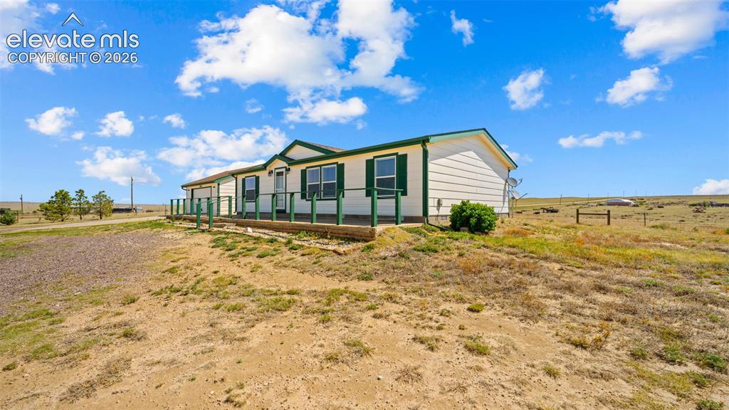 33975 Highway 94 Yoder, CO 80864 - Photo 3 of 40 Single-story residence featuring light-colored siding, a dark green roof trim, and coordinating green window shutters