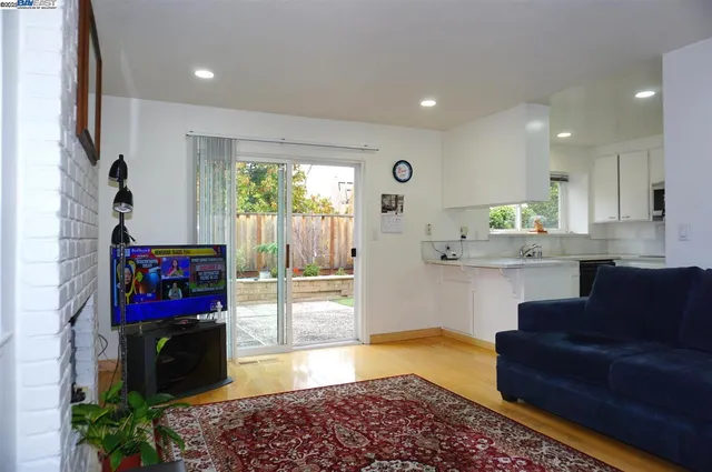 a living room with stainless steel appliances furniture a rug and a window