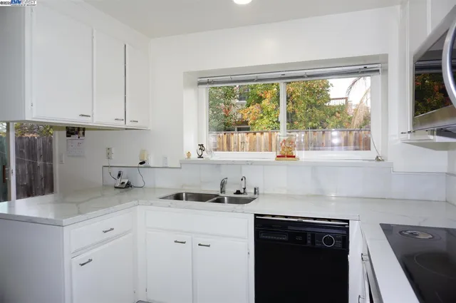 a kitchen with stainless steel appliances white cabinets and a window