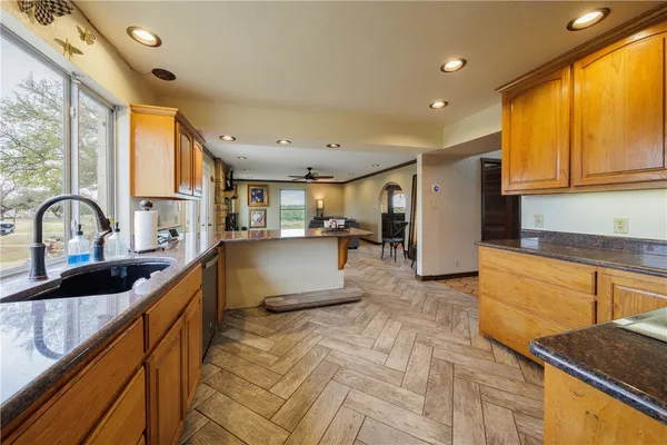 a large kitchen with kitchen island a large window appliances and cabinets