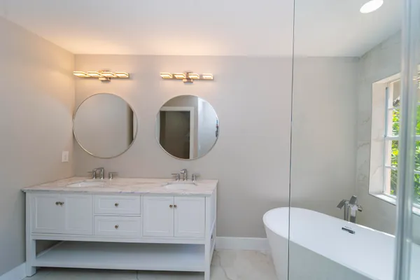 a bathroom with a double vanity sink mirror and bathtub