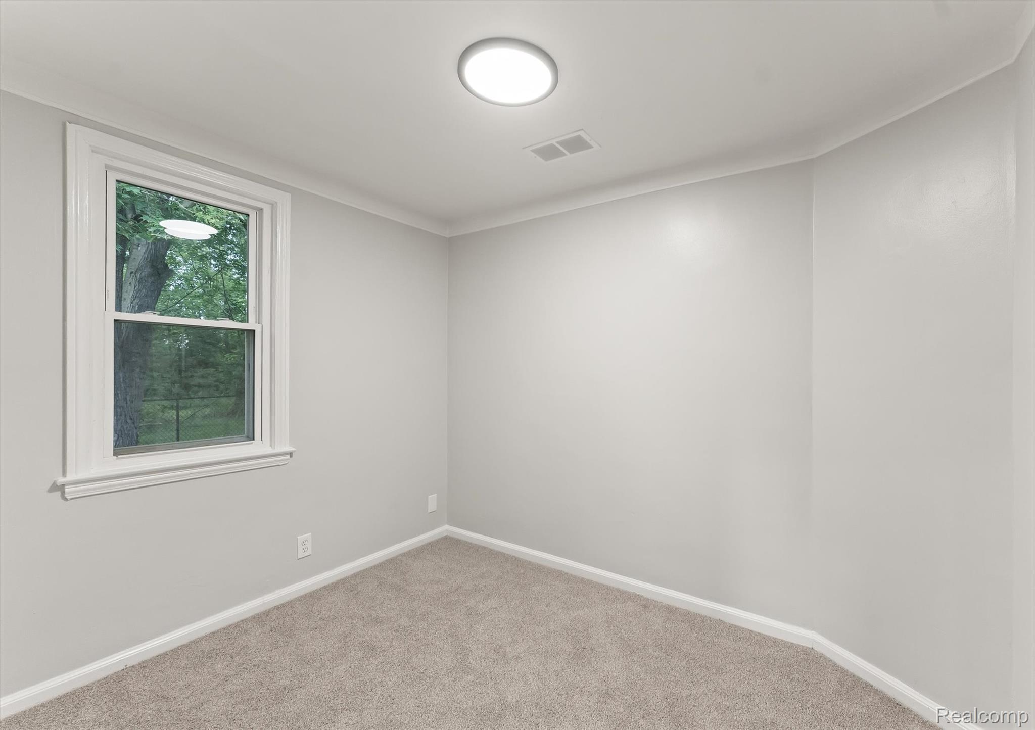 15564 Almont Road Allenton, MI 48002 - Photo 15 of 24 Neutral paint palette, carpeted flooring, double-hung window with white trim, and a ceiling-mounted light fixture