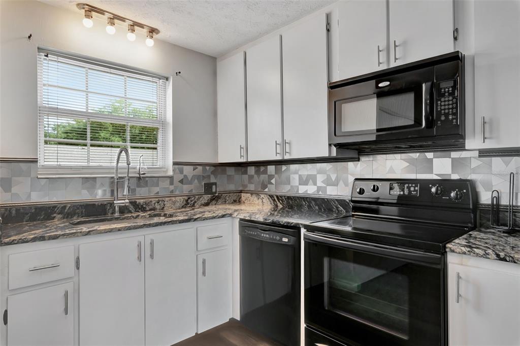 4216 Lake Underhill Road, Unit 6A28 Orlando, FL 32803 - Photo 5 of 18 a kitchen with stainless steel appliances granite countertop white cabinets granite counter tops and a wooden floors