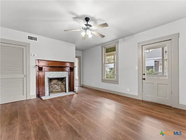 an empty room with windows fireplace and wooden floor