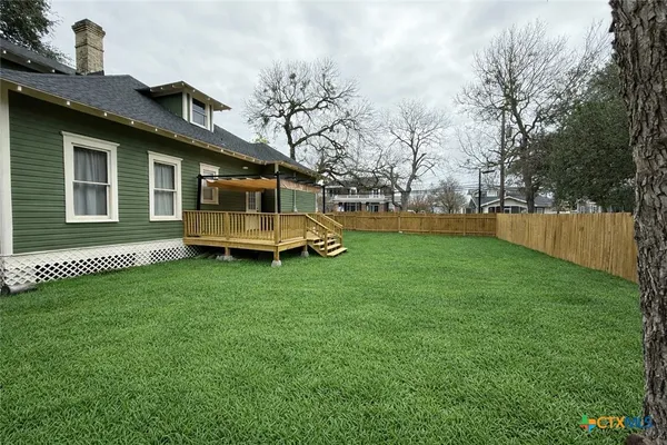 a backyard of a house with wooden fence and large trees
