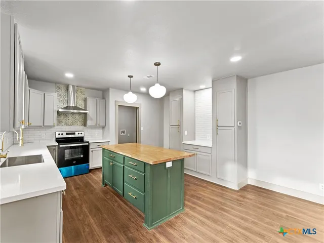 a large kitchen with stainless steel appliances granite countertop a stove refrigerator and a sink