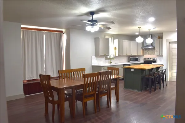 a dining area with a table chairs and a kitchen view