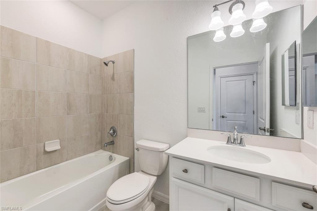 2434 Orchard Street Naples, FL 34120 - Photo 16 of 29 a bathroom with a sink a toilet a mirror a bathtub and shower