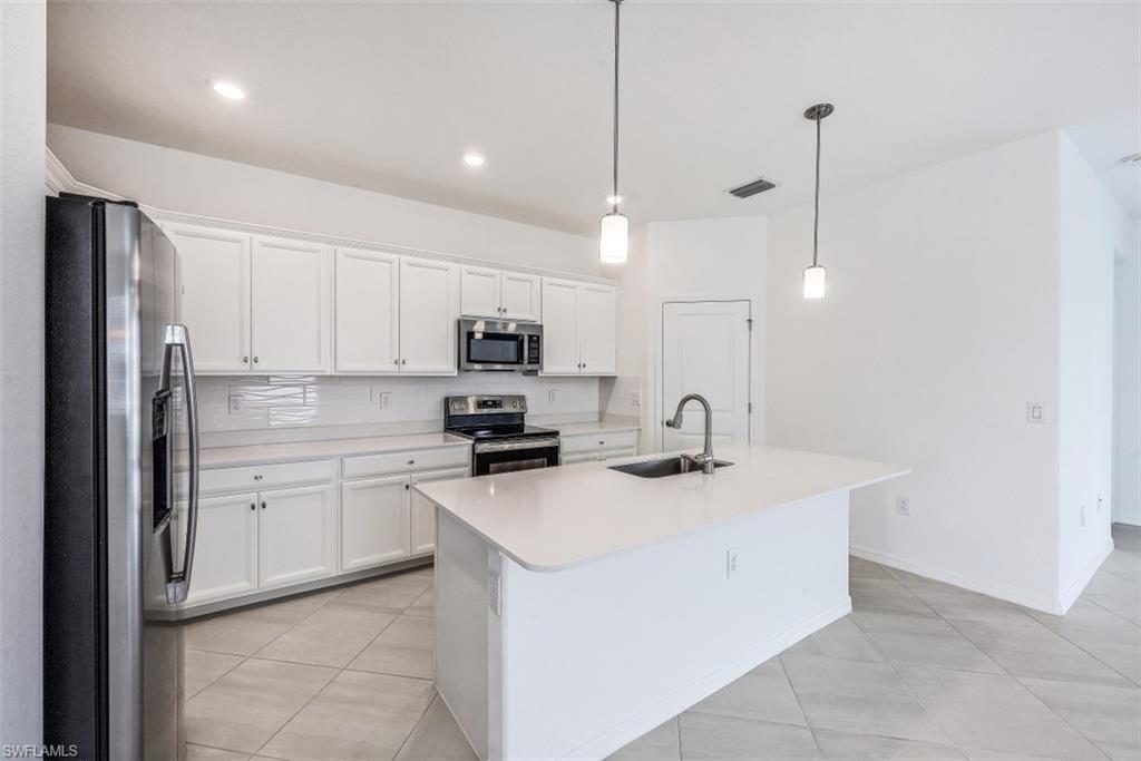 2434 Orchard Street Naples, FL 34120 - Photo 7 of 29 a kitchen with stainless steel appliances granite countertop a sink a stove a refrigerator and white cabinets with wooden floor